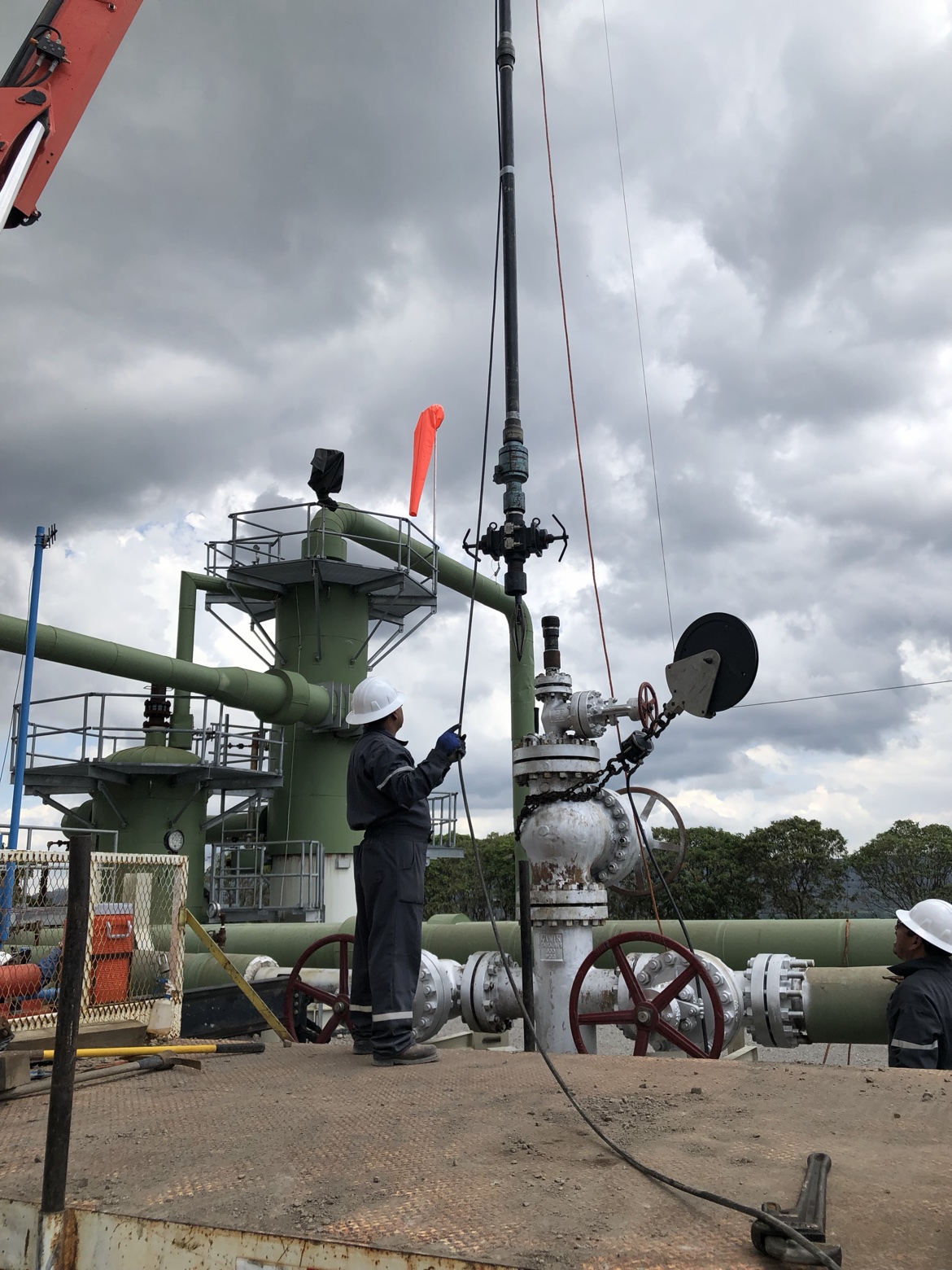Technicians operating a wireline cable at a wellhead with pressure control equipment