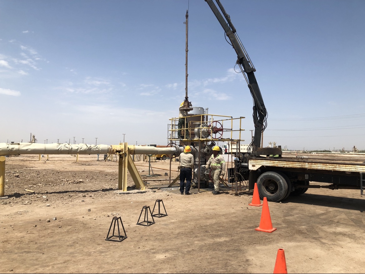 Crane truck and crew at a wellhead in a desert field